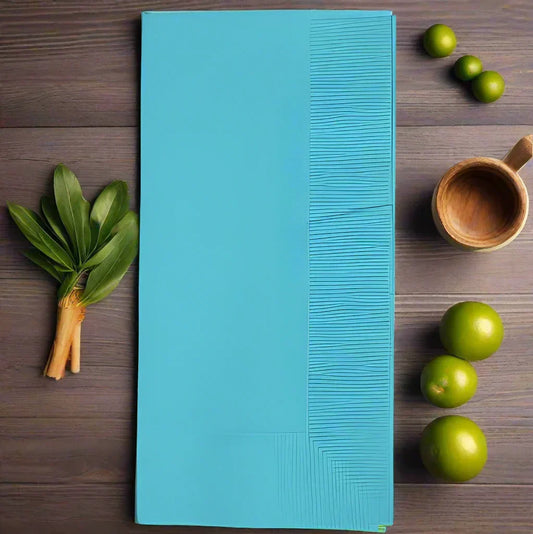 Blue disposable table mat with textured lines on wooden surface surrounded by fresh green limes and leaves