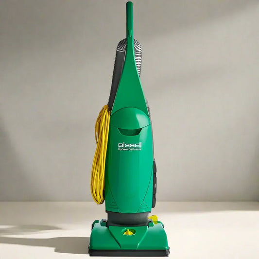 Green Bissell upright vacuum cleaner with yellow cord coiled on side on a plain floor