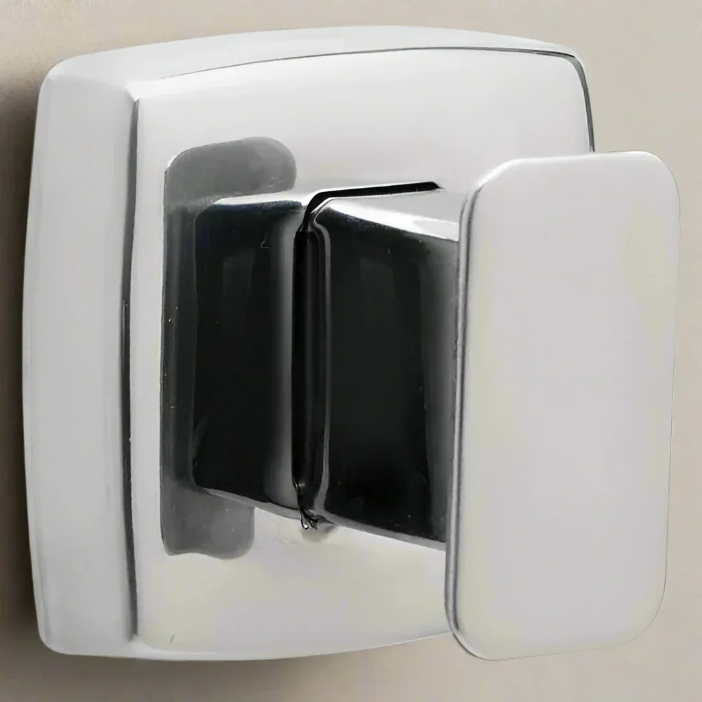 Close-up of shiny chrome wall hook with rectangular base mounted on beige wall