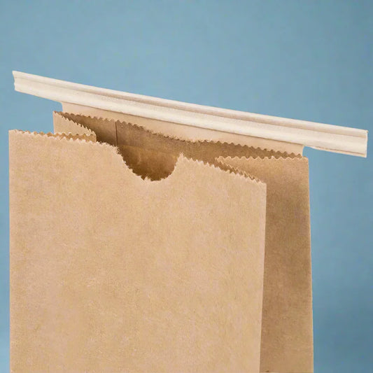 Close-up of a brown kraft paper bag with a zigzag top edge and a folded disposable straw on blue background