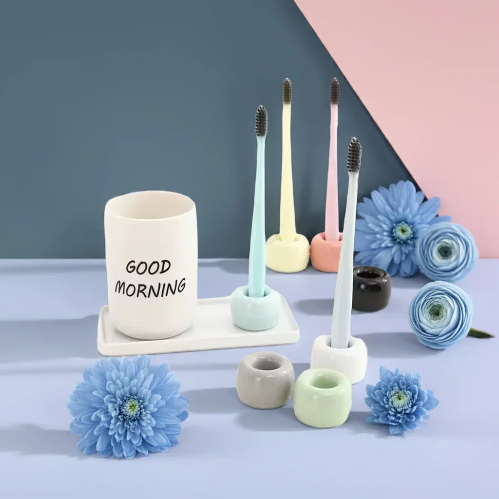 Colorful toothbrushes in pastel stands with a white cup saying 'Good Morning' on a blue and pink background with blue flowers