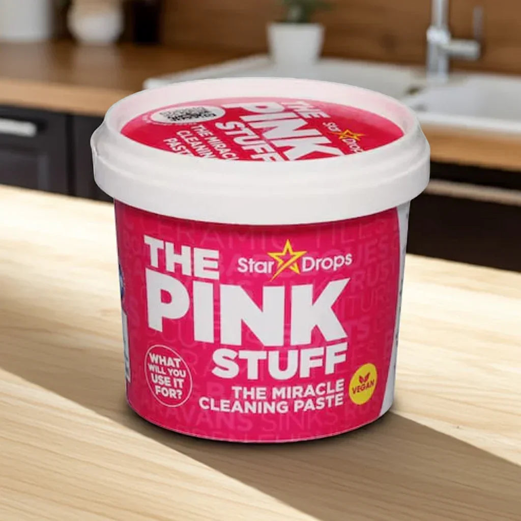 The Pink Stuff miracle cleaning paste container by Star Drops on a wooden kitchen countertop