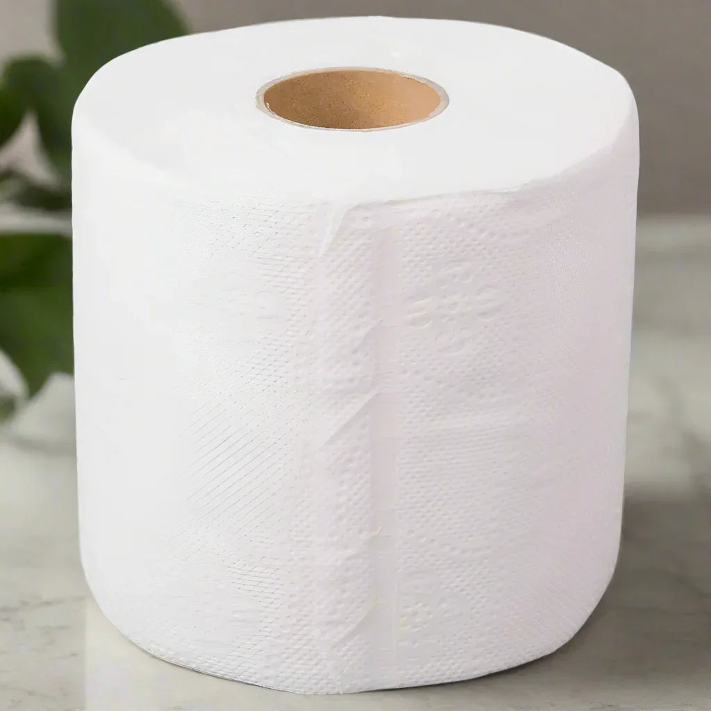 Close-up of a white disposable paper towel roll on a marble surface with blurred green leaves in background