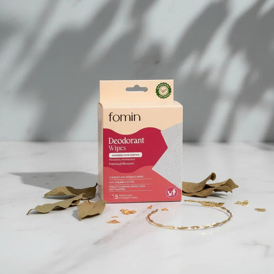 Fomin deodorant wipes packaging on minimalist white marble surface with dried leaves and golden ring