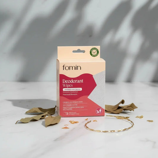 Fomin deodorant wipes packaging on minimalist white marble surface with dried leaves and golden ring