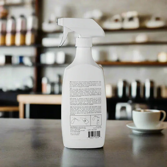 White spray bottle on countertop with blurred kitchen background and coffee cup