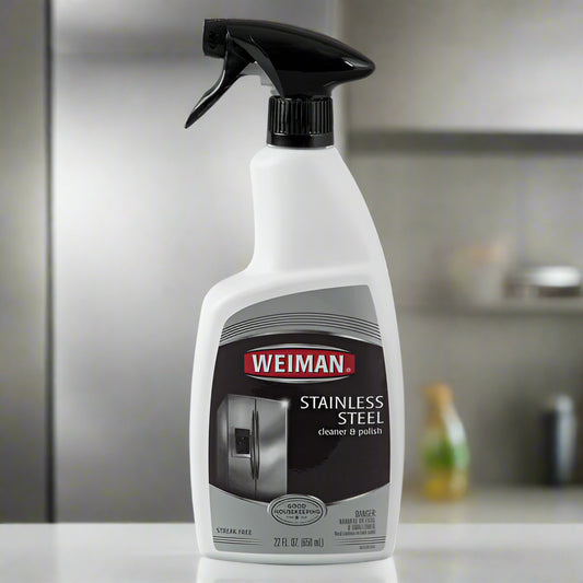 A bottle of Weiman Stainless Steel Cleaner & Polish, with a black trigger sprayer, sits on a counter in front of a stainless steel refrigerator. It is a product from One Use Classic.