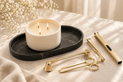 Luxury candle care gift set featuring a polished gold wick trimmer tool, a sleek gold electric plasma lighter, a black resin marble texture vanity tray, and a scented candle.