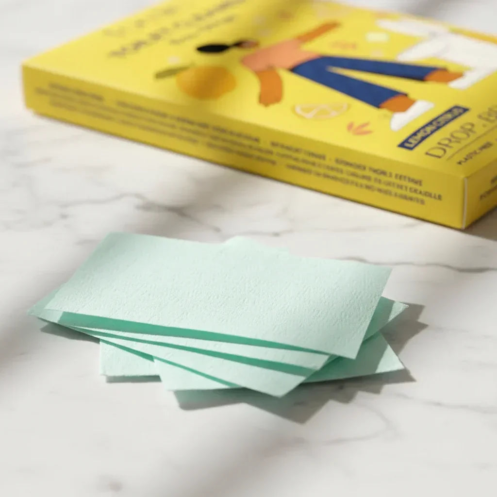 Close-up of light green toilet cleaner strips on marble surface with yellow packaging box in background