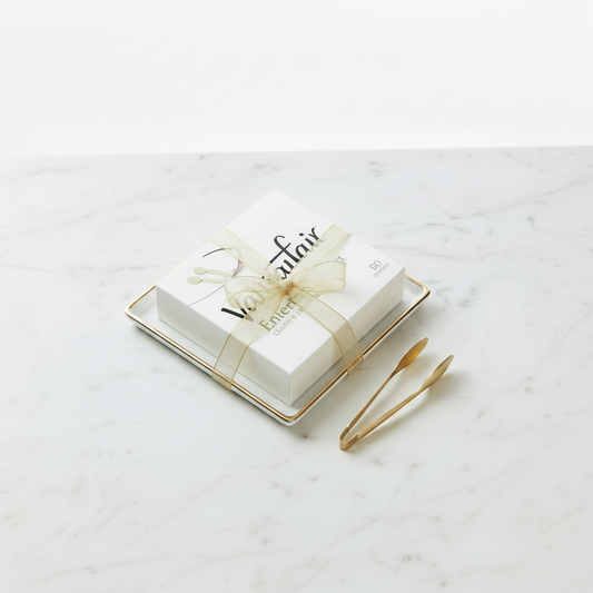 Vintage Gold & White Hosting Bundle featuring a 60-count pack of Vanity Fair Entertain Classic 3-ply napkins on a gold-edged square white porcelain tray, displayed next to American Metalcraft GVHT6 6-inch hammered gold vintage serving tongs.