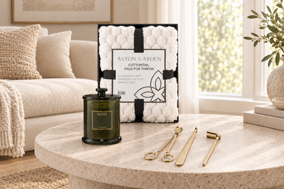 Wide view of gift set with white faux fur throw, candle, and gold candle care tools