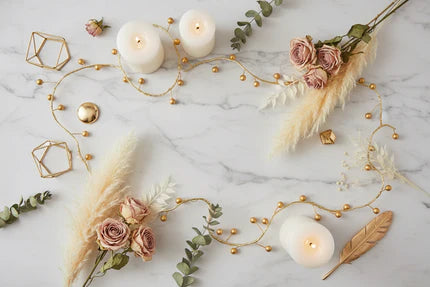 Gold Berry String Lights by OneUse Classic - decorative warm LED fairy lights on a gold wire, styled on a marble surface with white candles and dried flowers. Elegant indoor ambient lighting.
