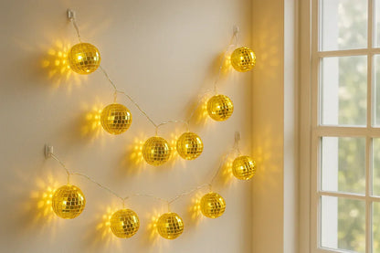 Gold disco ball string lights in daylight, hung with adhesive hooks