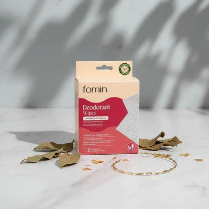 Fomin deodorant wipes packaging on minimalist white marble surface with dried leaves and golden ring