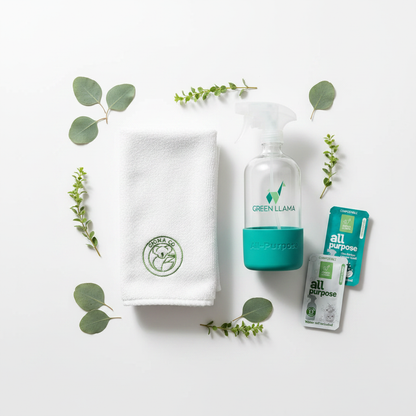 Flat lay of refillable glass cleaning spray bottle with teal silicone sleeve, dissolvable tablet packs, and reusable cleaning cloth.