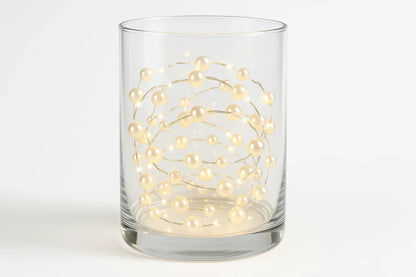 Pearl white bead string lights coiled in a clear glass vase