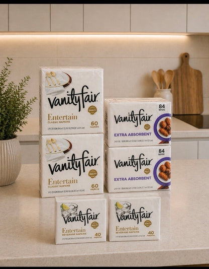 Vanity Fair 6-pack napkin bundle on a bright modern kitchen counter, featuring Entertain 3-ply, Extra Absorbent, and Beverage napkins.