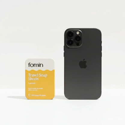 Fomin lemon travel soap sheets package next to a black iPhone for size comparison on white background