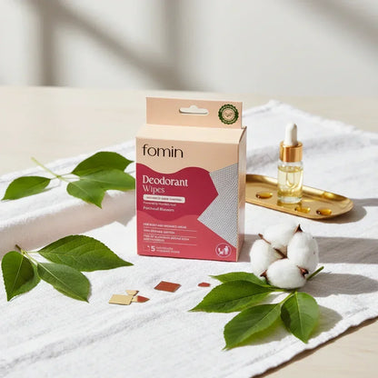 Fomin deodorant wipes box with Porchull Blossom scent on white cloth with green leaves, cotton, and glass dropper bottle