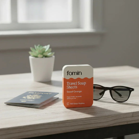 Fomin travel soap sheets in sweet orange scent on table with passport, sunglasses, and potted plant for travel hygiene