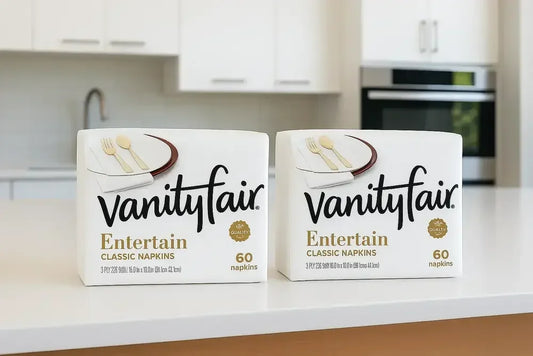 Two packs of 60 count Vanity Fair Napkins on a clean kitchen table - soft and absorbent disposable paper napkins.